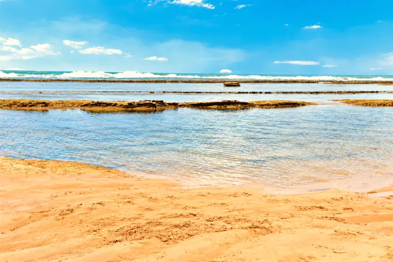 Arrecifes e o mar calmo vistos da areia