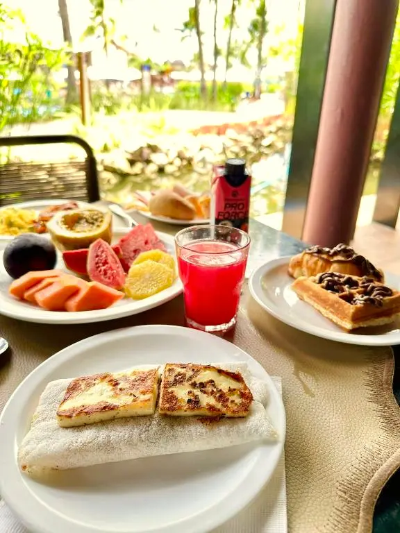 Frutas tropicais fatiadas, waffle e suco vermelho no café da manhã