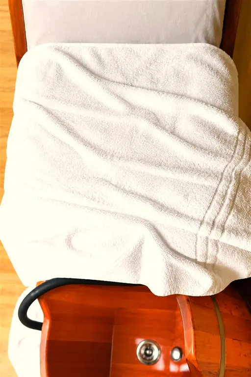 Massagem nos pés sobre maca coberta com toalha branca